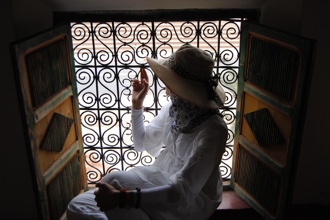a woman sitting on a window sill with a hat on