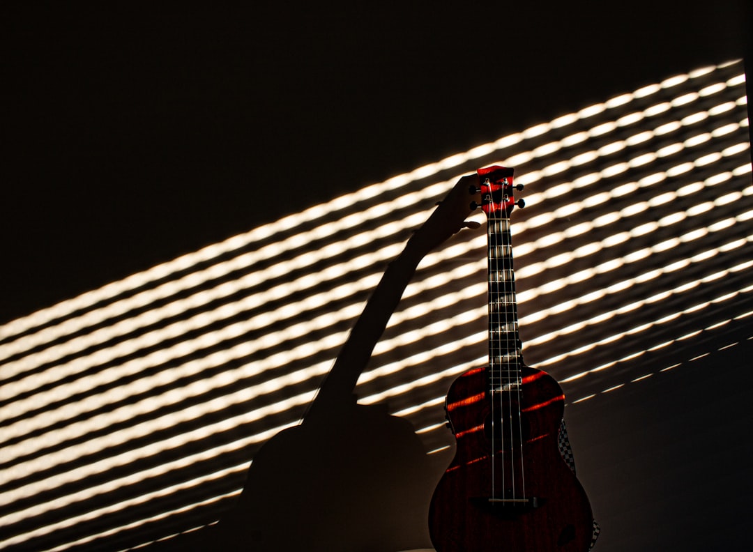 a red guitar sitting in front of a window